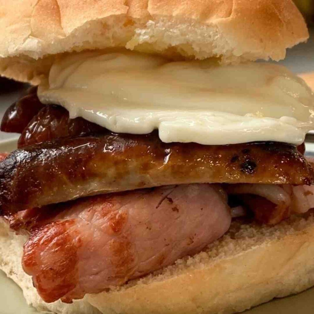 A breakfast soft cob containing a poached egg, sausage and bacon